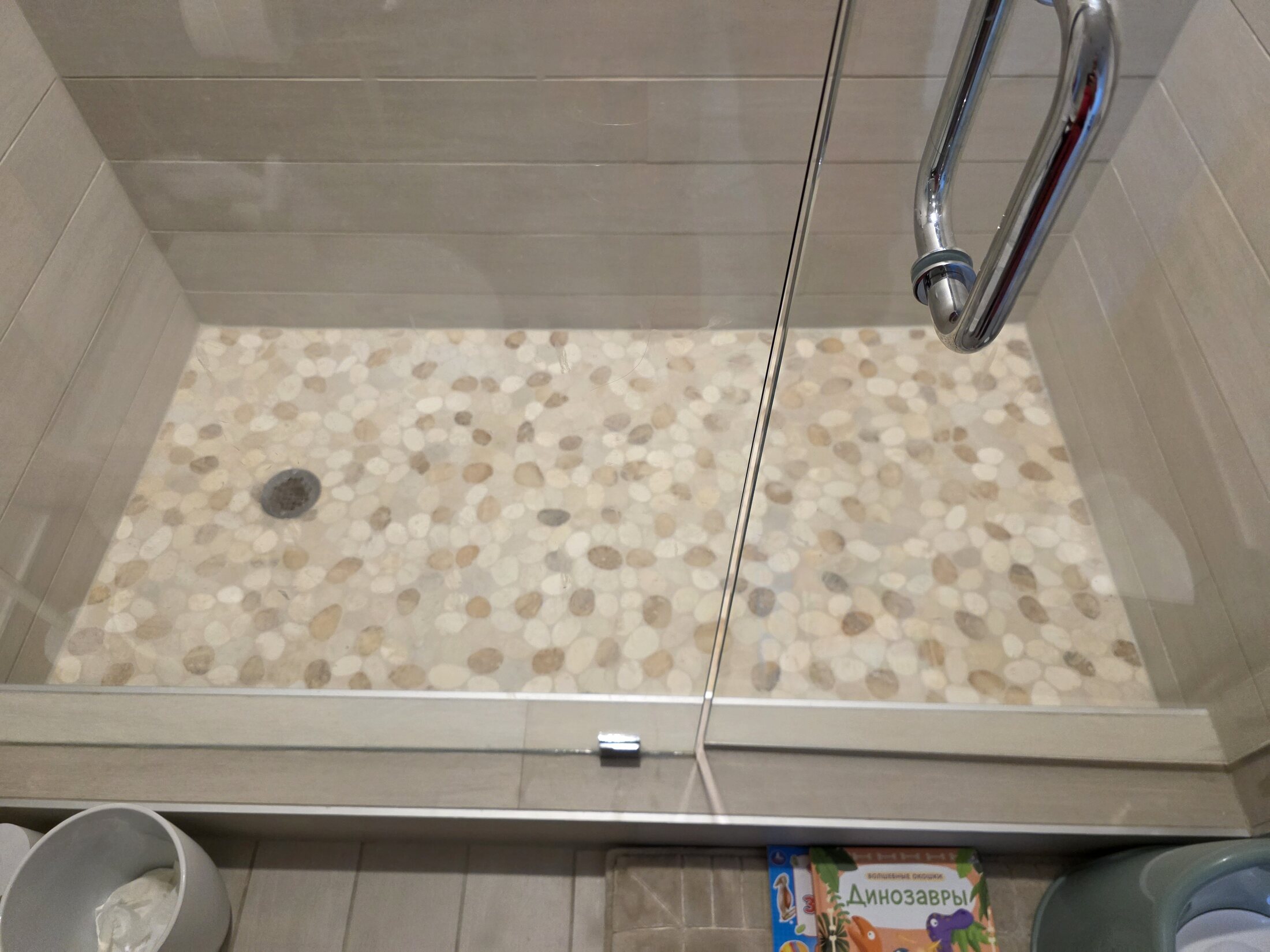 Completed shower with a river-stone mosaic floor and framed glass enclosure
