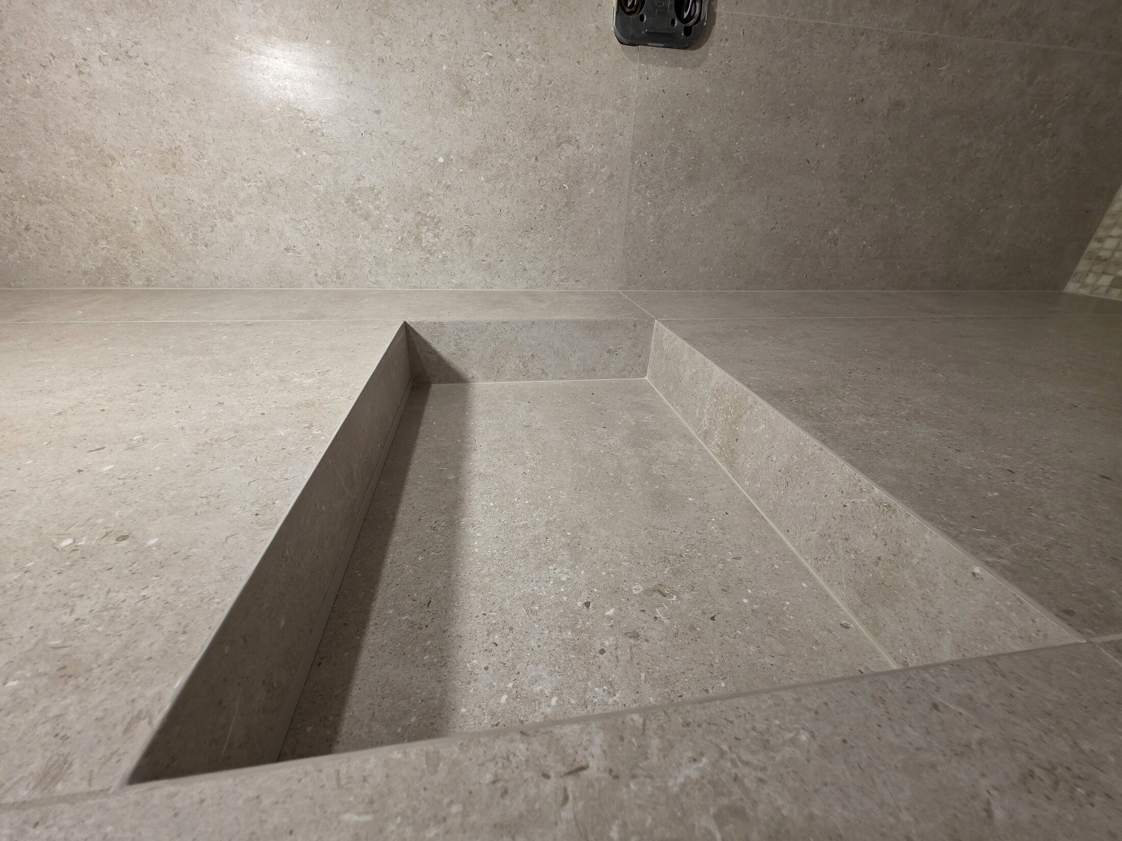 Large-format shower floor and bench prepared with clean geometry